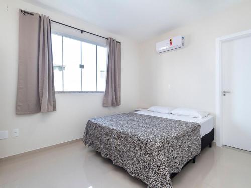 1 dormitorio con cama y ventana grande en Aluguel Apartamento 2 quartos sendo 1 suíte Bombas/SC, en Bombinhas