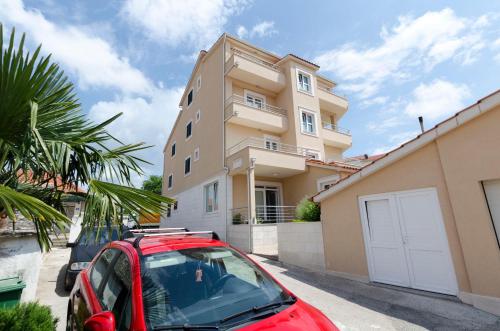 a red car parked in front of a house at Apartments Danica in Primošten