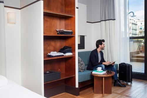 a man sitting on a couch in a room at Praktik Èssens in Barcelona