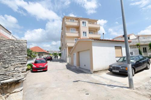two cars parked in a parking lot in front of a building at Apartments Danica in Primošten