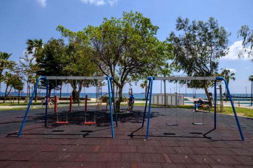 two swings in a park next to the water at Limassol Old Town Mansion in Limassol