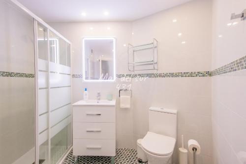 a white bathroom with a toilet and a sink at Mar del Sur Apartamentos- Piscina y Playa - PARKING GRATIS in Benalmádena