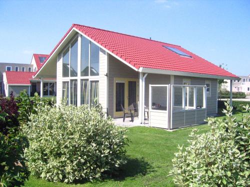 a small white house with a red roof at Villapark de Paardekreek in Kortgene