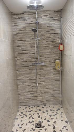 une douche dans une salle de bain avec un mur carrelé dans l'établissement Le jardin des secrets, à La Voivre