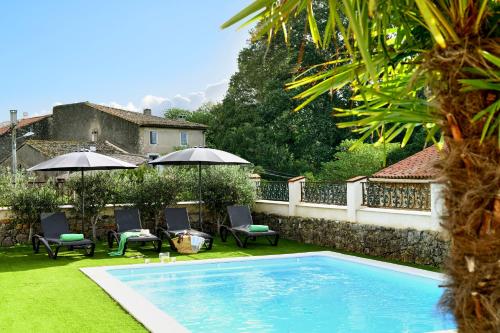 - une piscine dans une cour avec des chaises et des parasols dans l'établissement LOFT - Powered by LIEU -, à Villedaigne
