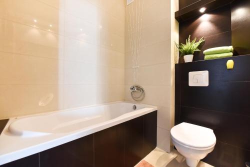 a bathroom with a bath tub and a toilet at APARTAMENT CENTRUM - 2 z miejscem parkingowym in Toruń