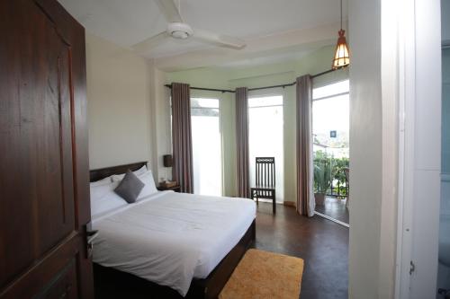 a bedroom with a white bed and a balcony at Villa Arunalu Kandy in Kandy