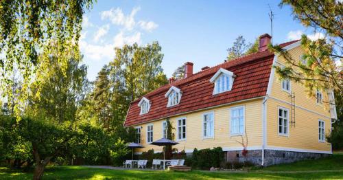 a large yellow house with a red roof at Tammiston Apartments in Naantali