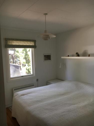a bedroom with a white bed and a window at Midtvejshuset in Rønne