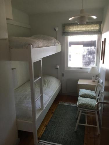 a bedroom with two bunk beds and a chair at Midtvejshuset in Rønne