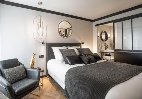 a bedroom with a bed and a chair and mirrors at Maisons du Monde Hotel & Suites - Nantes in Nantes