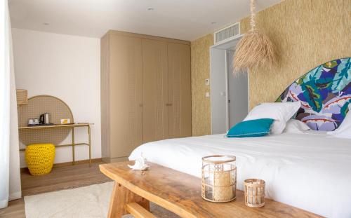a bedroom with a large bed and a wooden table at Les Bulles de Mer - Hotel & Spa sur la Plage in Saint-Cyprien