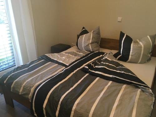 a bed with a striped comforter and pillows on it at Klause am grünen Hof in Friesoythe