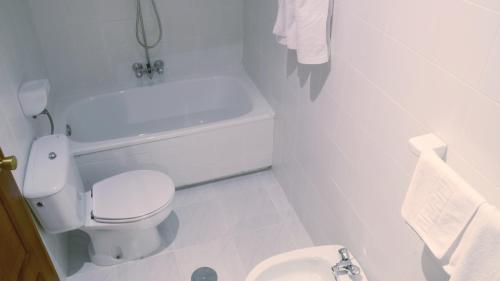 a white bathroom with a toilet and a bath tub at Hotel El Coloso in Jerez de la Frontera