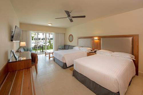 a hotel room with two beds and a television at Occidental Punta Cana - All Inclusive in Punta Cana