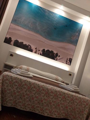 a painting hangs above a bed in a room at B&B L'Isola in Porto Cesareo