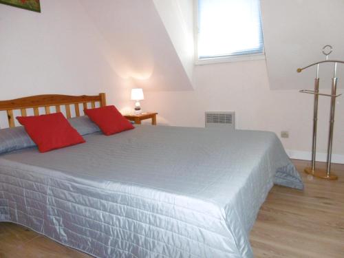 1 dormitorio con 1 cama grande y 2 almohadas rojas en Maisonnette Youenn, en Sarzeau