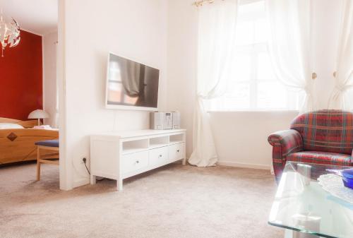 a white living room with a tv and a chair at Hotel Deutsches Haus in Heiligenhafen