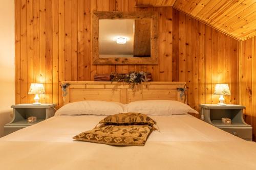 a bedroom with a large white bed with wooden walls at Haus Gobbis Transformational Retreat in the Dolomites in Gosaldo