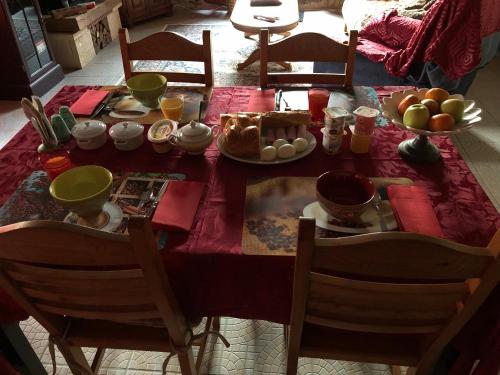 a dining room table with a red tablecloth with food on it at Chambres d'Hôtes Bastia et Bonifacio in Retiers