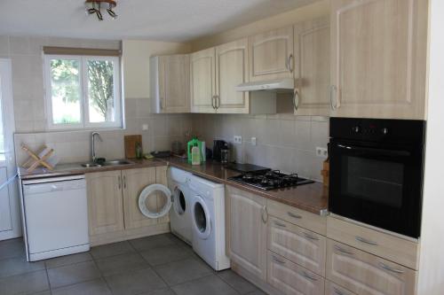 a kitchen with wooden cabinets and a washer and dryer at Les Pics Blancs in La Courtète