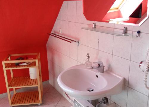 uma casa de banho com um lavatório e uma parede vermelha em Ferienwohnung auf Rügen in Maltzien em Losentitz