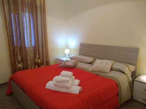 Un dormitorio con una cama roja con toallas. en Casa dei Girasoli, en Taormina