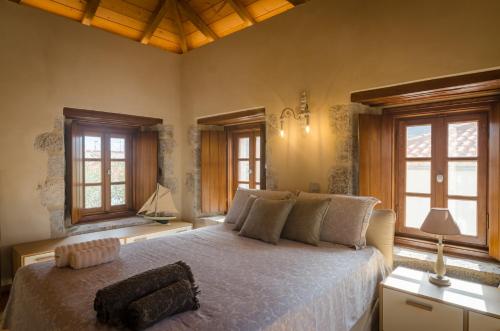 a bedroom with a large bed and two windows at Panthemis in Leonidio