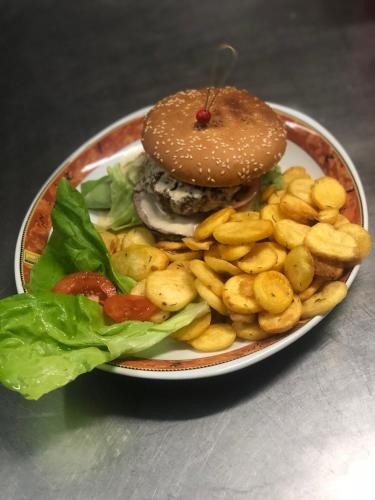 a plate with a hamburger and french fries and lettuce at Le Soleil D'or in Vimoutiers