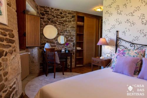 a bedroom with a bed and a desk in a room at Casa Rural as Bentinas in Milladoiro