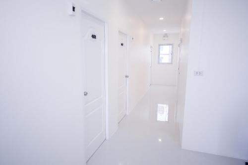 a white hallway with white walls and a window at U-need Guesthouse95 in Bangkok