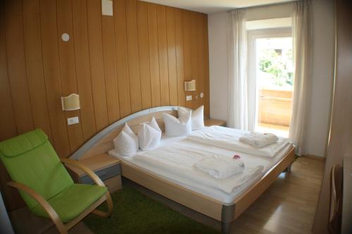 a bedroom with a bed and a chair and a window at Hotel Etschquelle in Resia