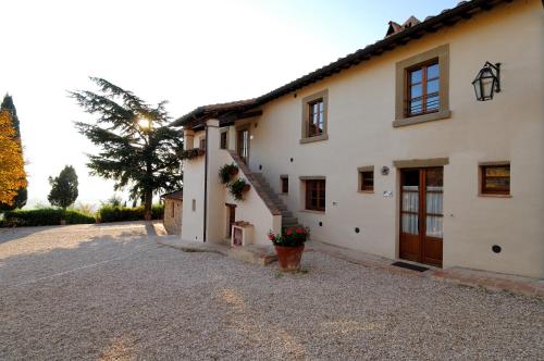 a large white house with a staircase in a driveway at Relais Borgo Torale in Passignano sul Trasimeno