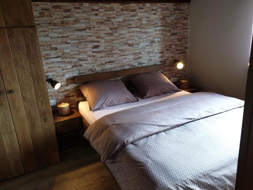 a bed in a bedroom with a brick wall at Plitvički San in Korenica