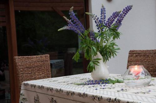 a vase of purple flowers on a table with a candle at Bobrowa Przystań in Czechyń