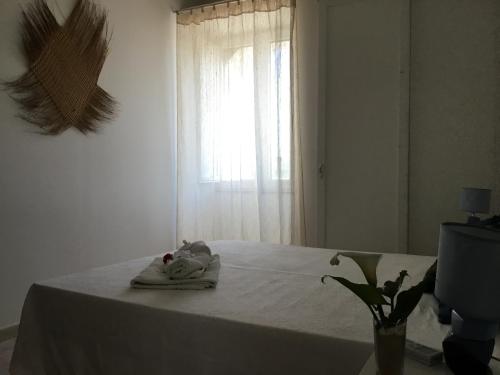 a white bed with a towel on it with a window at B&b Masseria Nova in Torre San Giovanni Ugento