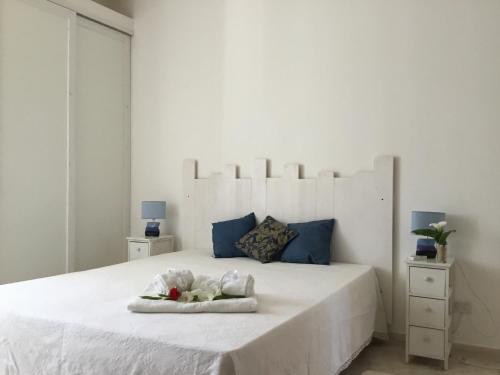 a white bedroom with a large white bed with blue accents at B&b Masseria Nova in Torre San Giovanni Ugento
