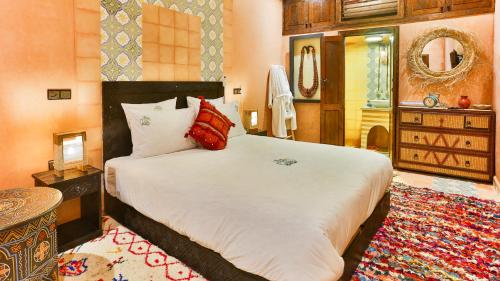a bedroom with a large white bed and a rug at ferme by Ikalimo in Ourika