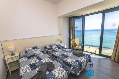 een slaapkamer met 2 bedden en uitzicht op de oceaan bij Apartments Vista Maritima By Villas Now Ltd in Playa Blanca