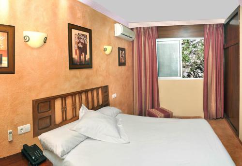 a bedroom with a large white bed with a window at Arrayanes Playa Almuñecar in Almuñécar