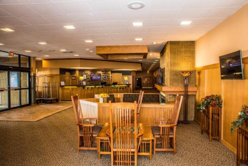 a restaurant with a table and chairs and a kitchen at Ramada by Wyndham Alpena in Alpena