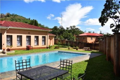 a house with a swimming pool and a table and chairs at Wadonda Suites in Zomba