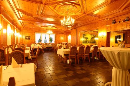 un ristorante con tavoli e sedie bianchi e un lampadario a braccio di Hotel Waldschlösschen a Füchten