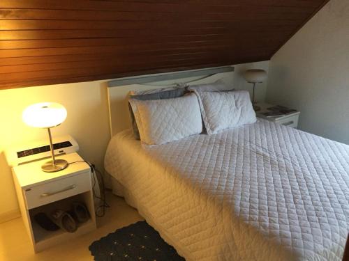 um quarto com uma cama branca e um tecto de madeira em Centro Gramado-LOCALIZAÇÃO PERFEITA em Gramado