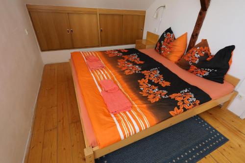 a bed with an orange blanket and pillows on it at Apartmán Skalka in Mnichovo Hradiště