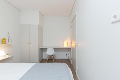 a white bedroom with a bed and a desk at Green Villas Douro in Gondomar