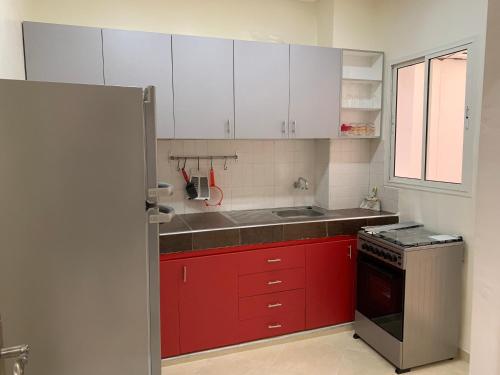 una pequeña cocina con armarios rojos y fregadero en Résidence Al Osra, en Agadir