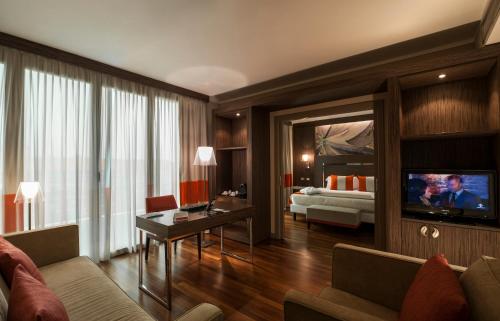 a living room with a couch and a living room with a television at Ramada Plaza by Wyndham Milano in Milan