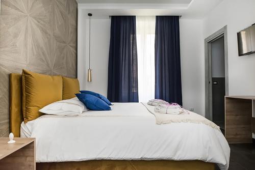 um quarto com uma cama branca com almofadas azuis e amarelas em My Love Suite em Roma