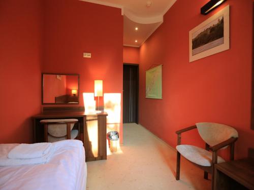 a bedroom with orange walls and a bed and a desk at Pensjonat Bajdarka in Suraż